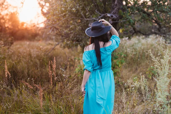 Retrato de una hermosa chica en un sombrero en un campo a la luz del atardecer —  Fotos de Stock