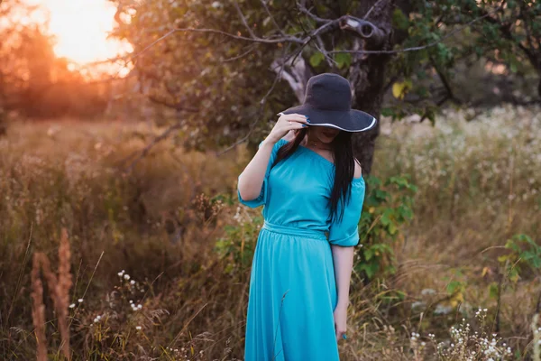 Retrato de una hermosa chica en un sombrero en un campo a la luz del atardecer —  Fotos de Stock