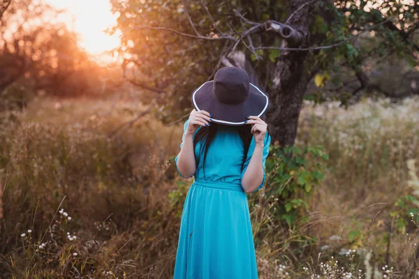 Retrato de una hermosa chica en un sombrero en un campo a la luz del atardecer —  Fotos de Stock