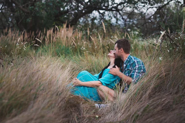 若い男と女が一緒に座っている屋外芝生のフィールド上のショット. — ストック写真