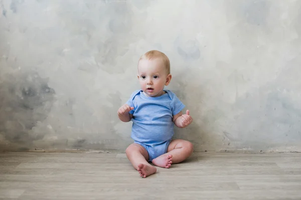 Kleiner Junge sitzt auf dem Boden neben der Wand — Stockfoto