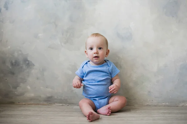 Kleiner Junge sitzt auf dem Boden neben der Wand — Stockfoto