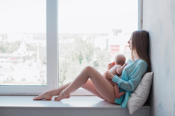 Младенец в нежных объятиях матушки Йонг у окна — стоковое фото