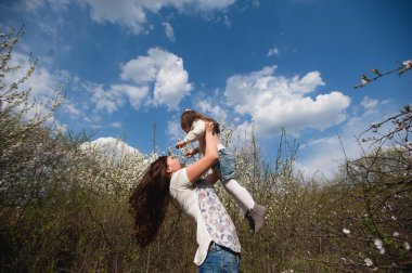 Anne kızı oynuyor mavi gökyüzü arka plan üzerinde baharda atar