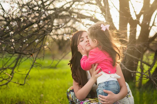 Mamá besos y abrazos hija en la naturaleza, familia, maternidad, niño —  Fotos de Stock