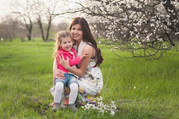 Mom kisses and hugs daughter on nature, family, motherhood, child