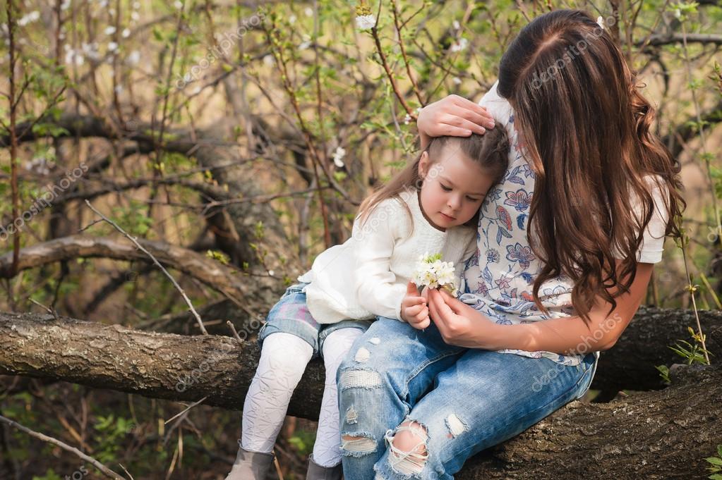 Mom kisses and hugs daughter on nature, family, motherhood, child ...