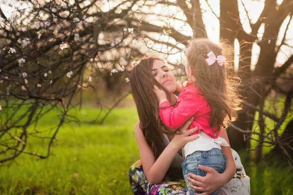 Mamá besos y abrazos hija en la naturaleza, familia, maternidad, niño —  Fotos de Stock