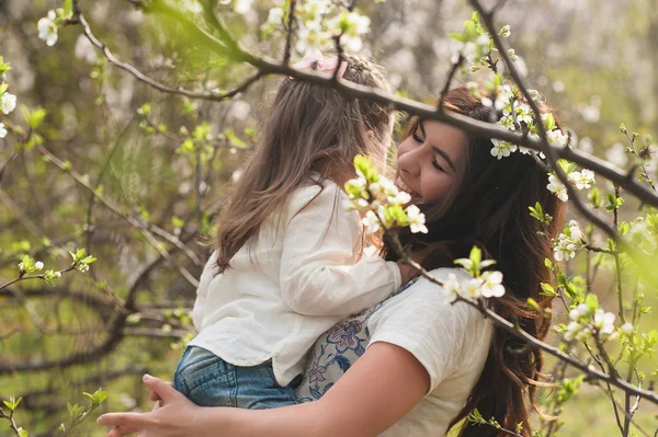 Mamá besos y abrazos hija en la naturaleza, familia, maternidad, niño —  Fotos de Stock