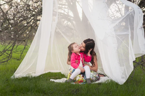 Mom kisses and hugs daughter on nature, family, motherhood, child