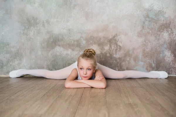 Little ballet dancer sitting on the splits in white bathing suit — Stock Photo, Image