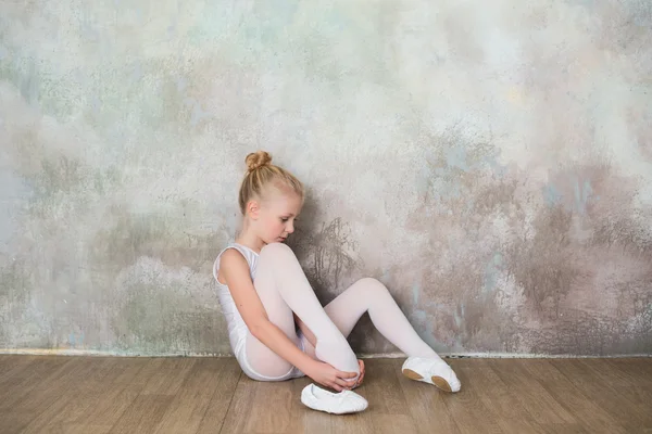 Little ballet dancer doing stretching before class in a white bathing suit — Stock Photo, Image