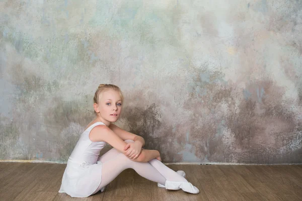 Little ballet dancer sitting white swimsuit, dance, sports, healthy lifestyle, ballet