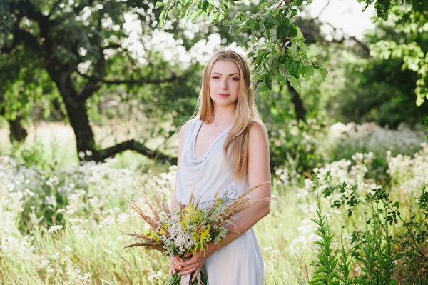 Красива блондинка на природі з букетом квітів — стокове фото