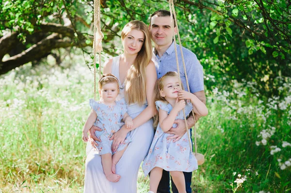 Mama und Papa spielen in der Natur und umarmen zwei Töchter — Stockfoto