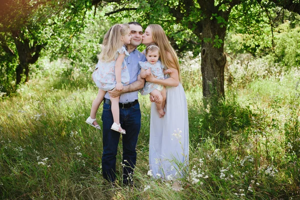 Mama und Papa spielen in der Natur und umarmen zwei Töchter — Stockfoto