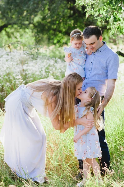 Mama und Papa spielen in der Natur und umarmen zwei Töchter — Stockfoto