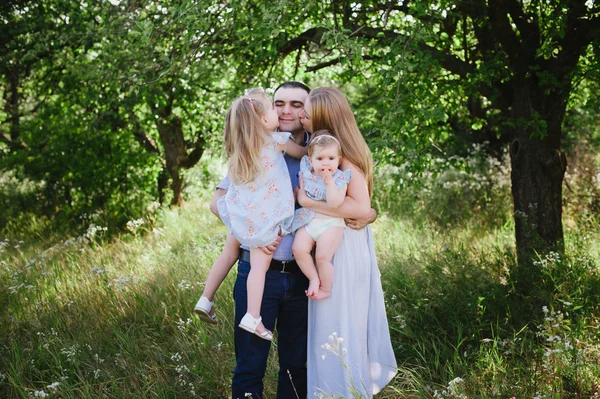Mama und Papa spielen in der Natur und umarmen zwei Töchter — Stockfoto