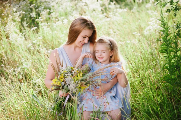 Moeder en dochter in de natuur met een bouquet van veldbloemen Rechtenvrije Stockfoto's