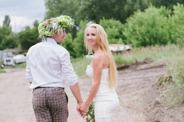 Glada unga par med en bukett och en krans omfamnar och kysser — Stockfoto