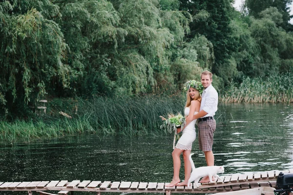 Belo casal com um buquê na ponte com um gato branco — Fotografia de Stock