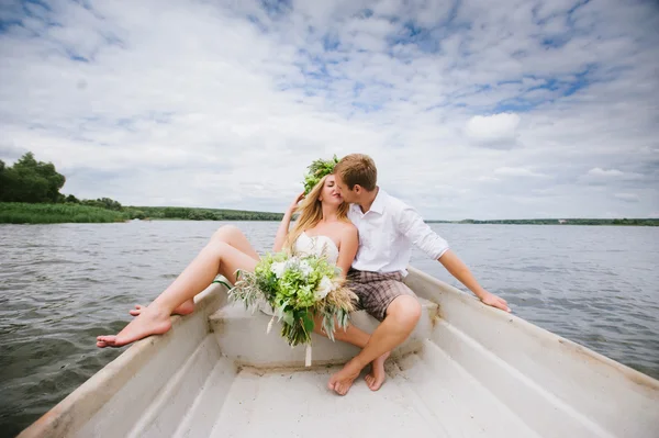 Glada unga par med en bukett och en krans omfamnar och kysser — Stockfoto