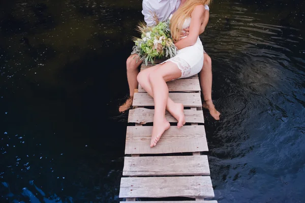 Retrato de una sensual pareja joven abrazándose en un puente de madera sobre un fondo —  Fotos de Stock