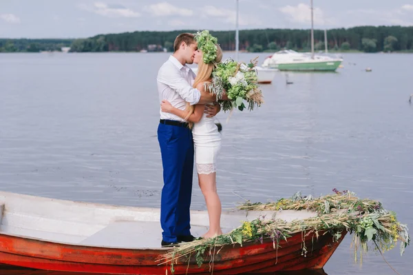 Glada unga par med en bukett och en krans omfamnar och kysser — Stockfoto