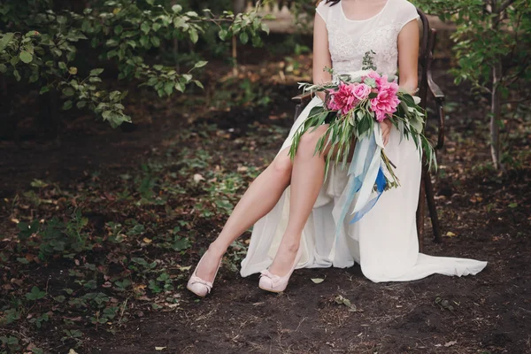 Schöne Hochzeitsschuhe mit Stöckelschuhen und einem Strauß bunter Blumen auf einem Vintage-Stuhl in der Natur — Stockfoto