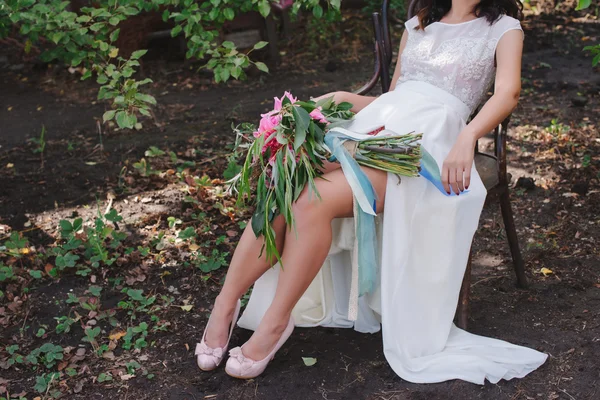 Hermosos zapatos de boda con tacones altos y un ramo de flores de colores en una silla vintage en la naturaleza —  Fotos de Stock
