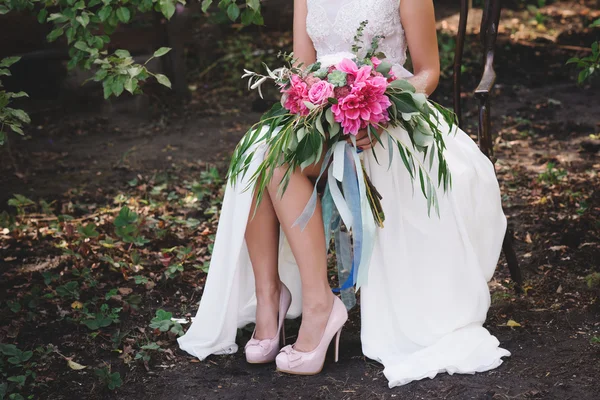 Belle scarpe da sposa con tacchi alti e un mazzo di fiori colorati su una sedia vintage sulla natura — Foto Stock