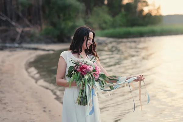 Piękna dziewczyna z bukietem kwiatów jest bukiet na plaży — Zdjęcie stockowe