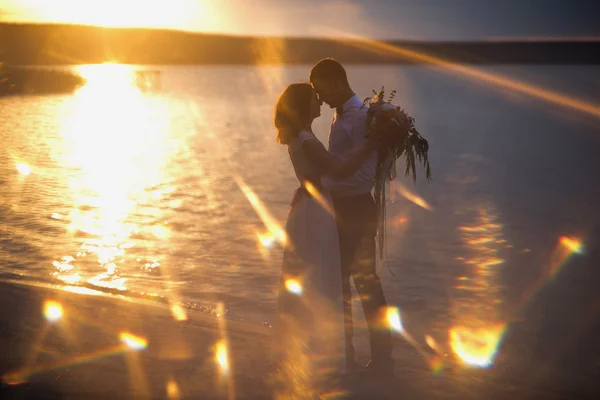 Noiva e noivo, beijando ao pôr do sol em uma bela praia tropical — Fotografia de Stock