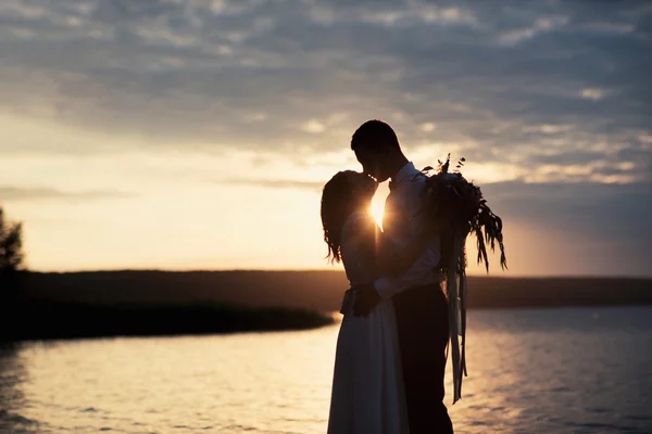 花嫁と花婿、美しい熱帯のビーチの夕日にキス — ストック写真