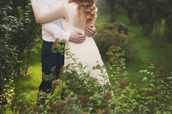 Жених и невеста в завесе стоят и держатся за руки на природе — стоковое фото
