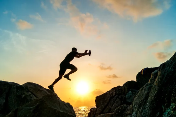 Mann springt auf Felsen gegen das Meer — Stockfoto