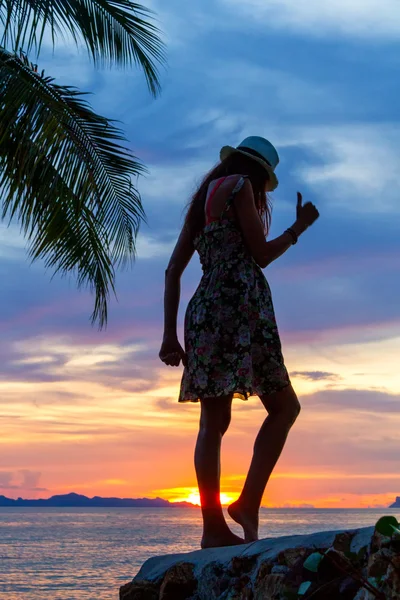 熱帯の夕日の背景を海に岩の上を踊っている女の子のシルエット — ストック写真