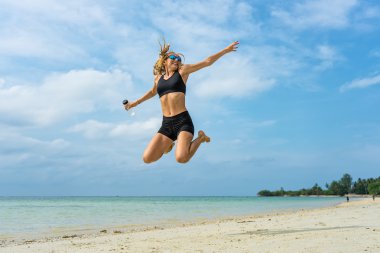 Genç atletik kadın tropik sahilde atlama