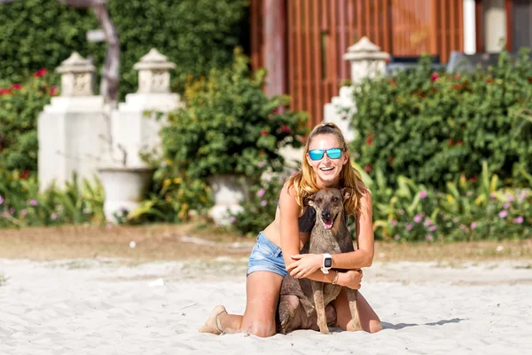 Young woman playing with dogs on the beach — Stock Photo, Image