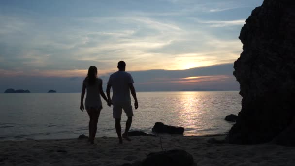 Jovem casal caminha ao longo da praia e assistindo pôr do sol — Vídeo de Stock