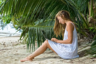 Koh Samui, Tayland bir dizüstü bilgisayar ile tropikal bir sahilde oturan genç kadın