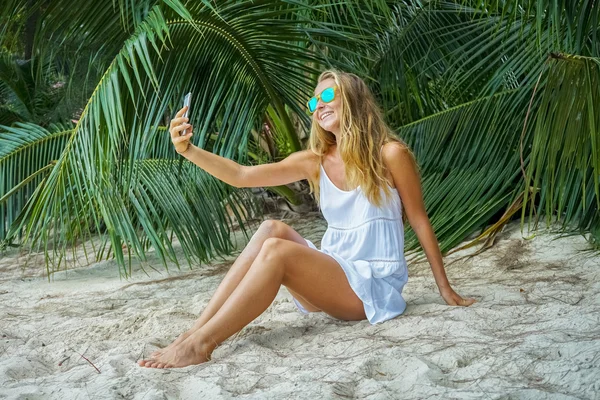 Молода жінка сидить на тропічному пляжі і фотографується — стокове фото
