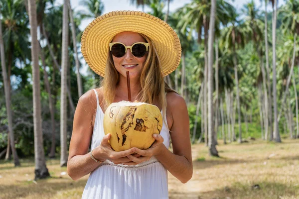 Молода жінка зі свіжим кокосовим горіхом в руці, що йде через джунглі — стокове фото