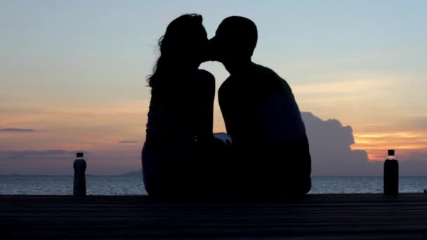 Pareja joven sentada en el muelle al atardecer — Vídeos de Stock