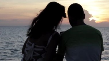 Genç çift günbatımı arka plan iskelede oturup...