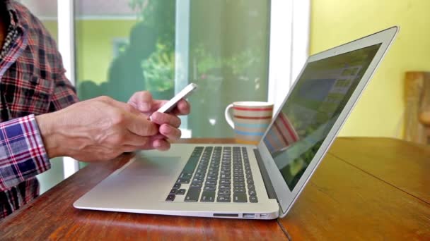 Man typing on laptop and phone outdoors — Stock Video