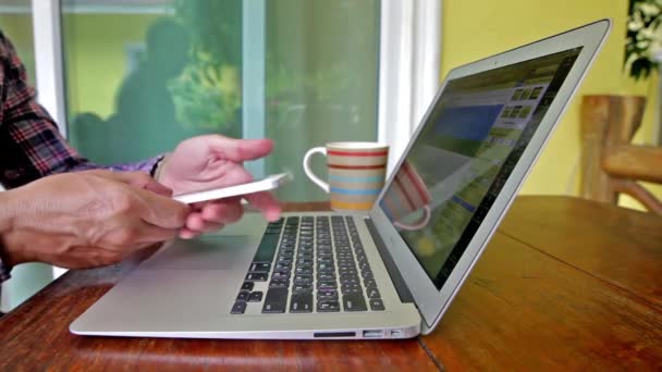 Man te typen op de laptop en telefoon buitenshuis — Stockvideo