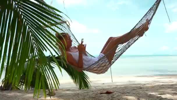 电话在吊床上海滩上的年轻女子 — 图库视频影像