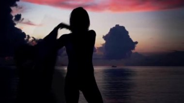 Genç kadın sahilde günbatımı arka plan üzerinde dans