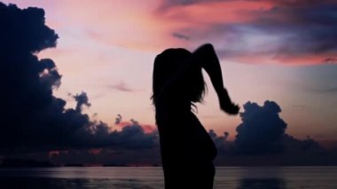 Genç kadın sahilde günbatımı arka plan üzerinde dans